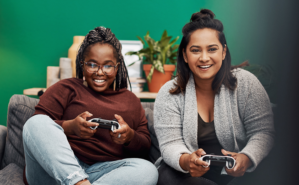 two women sitting on couch playing video games