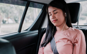 young woman with her eyes closed travelling in a car listening to music
