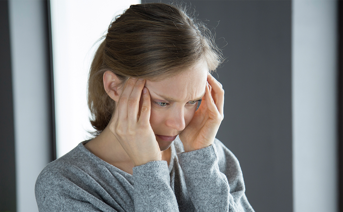 Woman who has a headache holding her hands on her temples