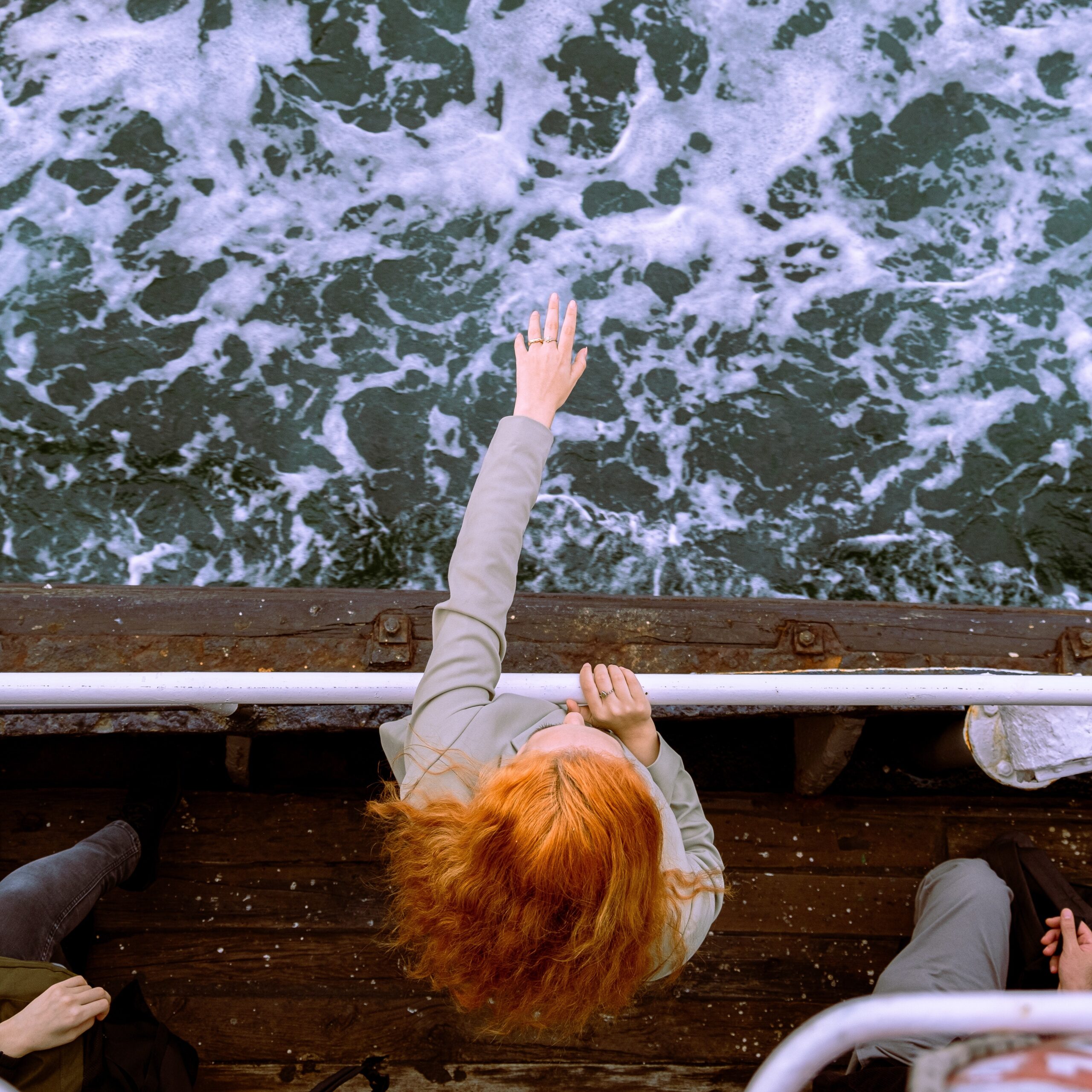 woman reaching out over the deck of. a boat