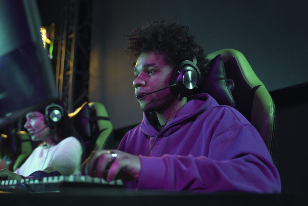 man playing video games on computer with headset on.